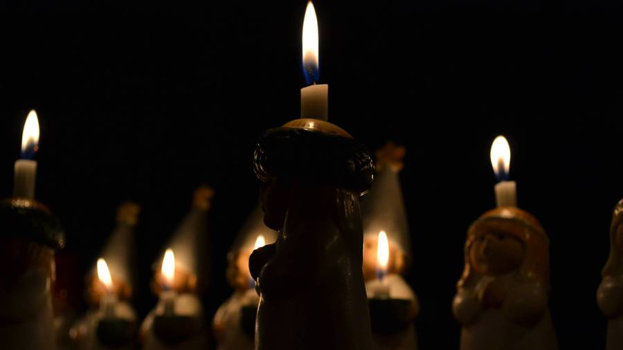 Bilden visar flera stearinljus som brinner i mörkret.