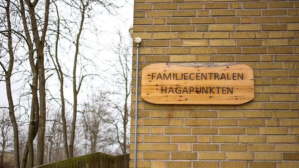 Utanför familjecentralen i Åstorp - på en skylt på husväggen står det "Famijlecentralen Hagapunkten".