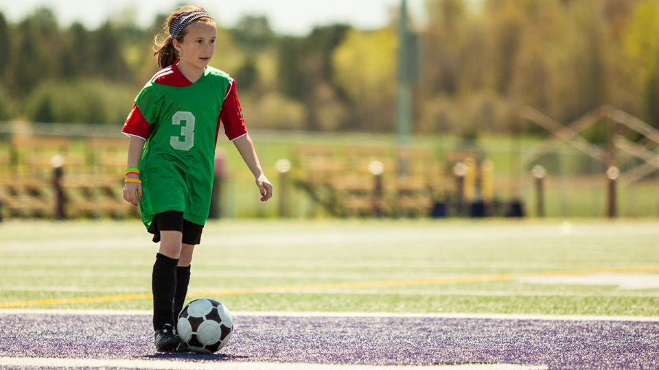 En ung flicka spelar fotboll.