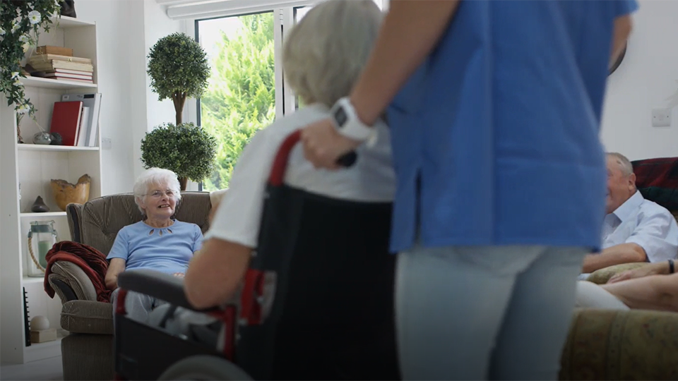 En äldre dam sitter i en rullstol och möter 