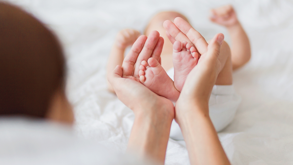 Händer håller i små bebisfötter
