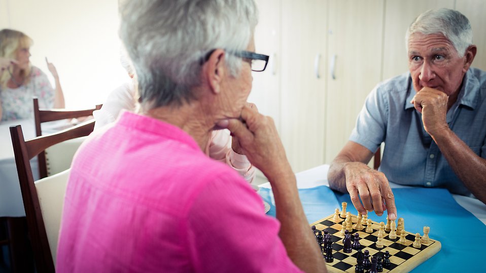 Äldre kvinna och man spelar schack