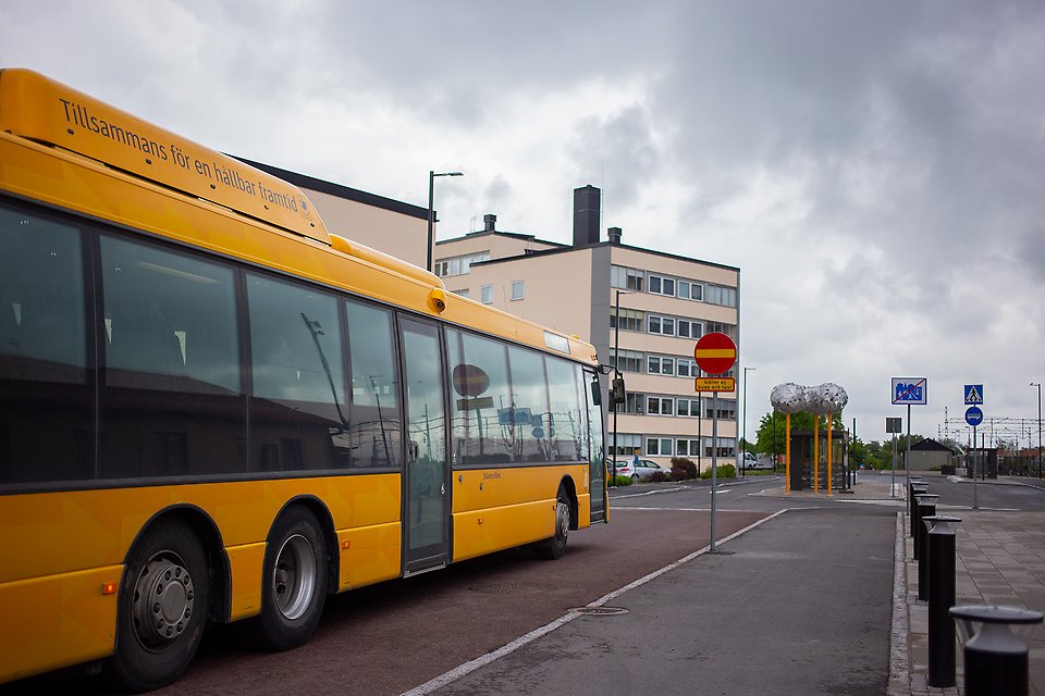 En gul buss kör förbi stationshuset i Åstorp.