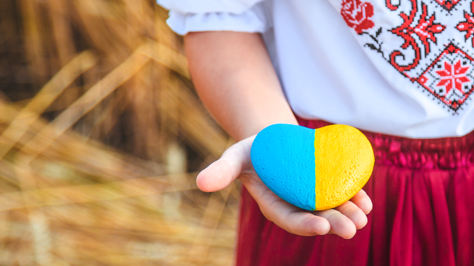Barn håller i en hjärtformad sten målad i Ukrainas flaggas färger.
